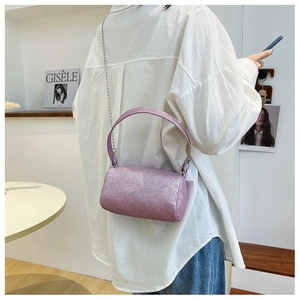 Détail d'un sac cylindre à paillettes roses avec chaîne argentée et poignée supérieure