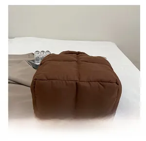 Detail showing the wear-resistant quilted bottom of a brown padded puffer tote bag