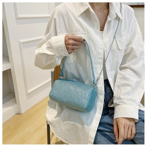 Vue détaillée du sac cylindre bleu clair scintillant avec chaîne argentée sur un modèle