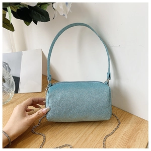 Détail d'un sac cylindre à paillettes bleu clair avec bandoulière chaîne argentée