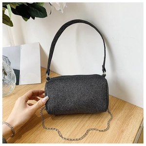 Détail du sac baril gris pailleté avec bandoulière chaîne sur table en bois