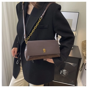 Détail d'un sac à main en cuir marron foncé avec fermoir doré vintage et bandoulière