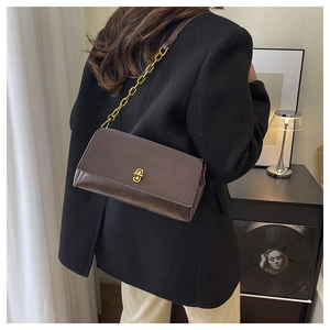 Détail du sac à main en cuir marron foncé avec fermoir tournant doré et bandoulière