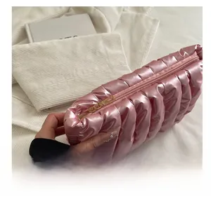 Close-up of the smooth golden metal zipper and quilted satin fabric on a pink pouch
