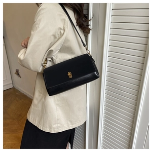 Détail du sac à bandoulière en cuir noir avec un fermoir rotatif en métal doré unique