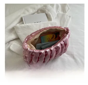 Detail view of pink metallic dumpling bag storage capacity with phone and wallet inside