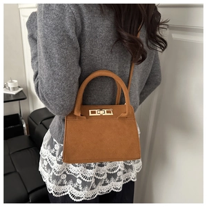 Close-up of matte mustard yellow handbag with gold square buckle on casual outfit