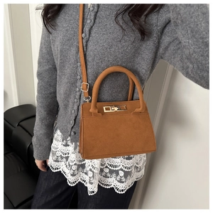 Brown frosted leather trapezoid bag with gold twist lock shown on model with gray sweater