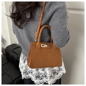 Detail of vintage matte brown handbag showing gold metal lock and rich suede texture