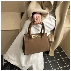 Macro detail of dark brown suede handbag with elegant golden metal twist lock closure