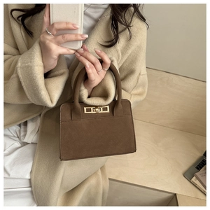 Close-up of a vintage dark brown matte handbag with golden turn-lock clasp detail