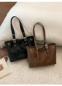 Close-up of black and brown retro tote bags with silver eyelets and adjustable straps