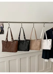 Detail view of four minimalist tote bags with studs in brown, black, khaki, and white