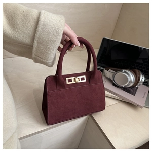 Close-up of burgundy suede handbag featuring premium texture and gold metallic buckle