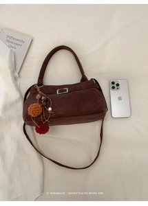 Flat lay of a brown suede tote bag with colorful pompom charm and minimalist retro vibes