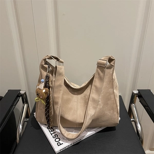 Khaki hobo shoulder bag in soft matte texture with cute bear pendant on a chair
