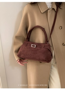 Close-up of suede crossbody bag in dark burgundy with metallic buckle and leather strap