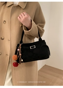 Close-up of black suede tote bag with silver square buckle and colorful pompom pendant