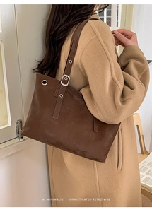 Detail of dark brown retro rivet tote bag on shoulder with minimalist sophisticated vibe