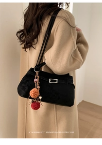 Detail view of black suede tote bag with silver buckle and colorful fur ball pendant