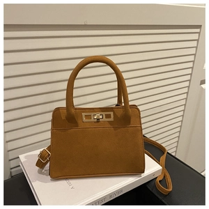 Detail view of brown matte suede handbag with gold turn-lock and adjustable shoulder strap