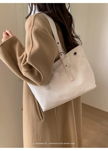 Detailed view of white tote bag strap with metal buckles and eyelets on shoulder