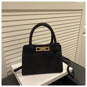 Detail of black matte suede handbag featuring a gold metallic twist lock and top handle