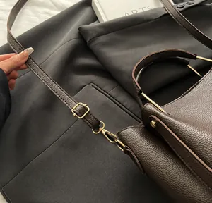 Détail de la boucle dorée réglable et de la poignée sur le sac en cuir marron grainé