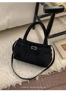 Detail of a retro black suede tote bag featuring a silver rectangular metal buckle