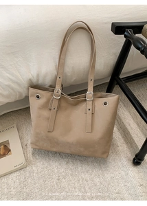 Top-down view of a beige minimalist tote bag with silver metal eyelets and dual straps