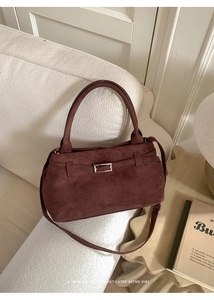 Macro view of vintage burgundy faux suede tote with metallic buckle and strap details