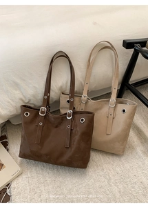 Detailed view of leather tote bags with metal eyelets and adjustable shoulder straps