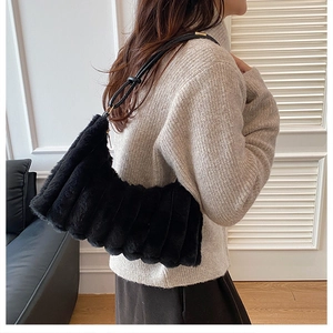 Detail of black faux fur shoulder bag with vertical texture and gold hardware accents