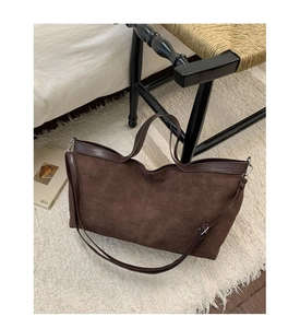 Dettaglio della borsa tote in pelle scamosciata marrone scuro su tappeto