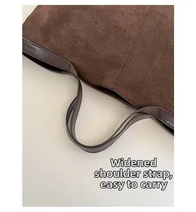 Dettaglio dei manici larghi e texture in pelle scamosciata della borsa marrone