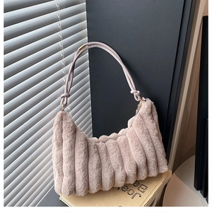 Detail of pink plush shoulder bag featuring vertical pleat textures and knotted strap design