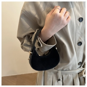 Detail of a black crescent moon bag featuring suede finish and gold metal hardware
