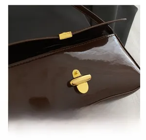 Macro shot of dark brown patent leather with a polished gold metal twist lock buckle