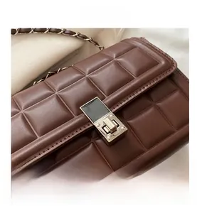Close-up of brown quilted leather texture with silver metal twist lock and chain strap