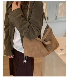 Dettaglio di una borsa tote in pelle scamosciata marrone con tracolla regolabile