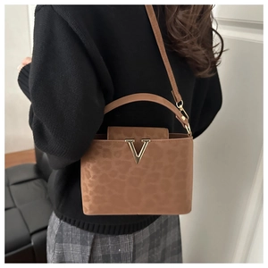 Detail van luipaardprint handtas met goudkleurig V-logo en matte suede-look textuur