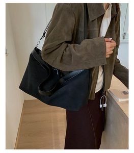 Dettaglio laterale di una grande borsa tote nera con manici e finiture in pelle premium