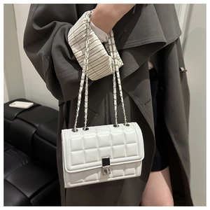 Detail view of the white quilted chain bag with silver twist lock and glossy texture