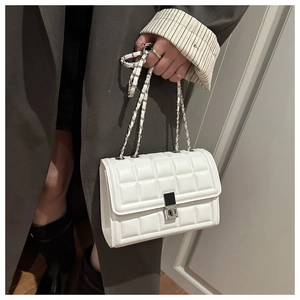 Detail of white quilted crossbody bag featuring silver turn-lock and chain strap detail