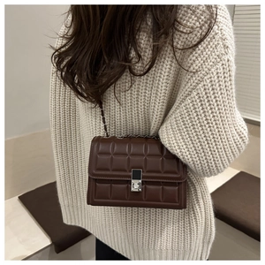 Rear view of dark brown quilted chain crossbody bag styled with white knit sweater