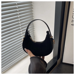 Close-up of black suede crescent bag with smooth leather strap and golden metal hardware