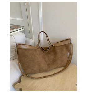 Dettaglio borsa tote in pelle scamosciata marrone con manici su sgabello di legno