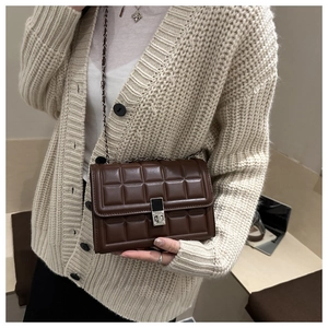 Detail of dark brown quilted crossbody bag with silver square lock and chain strap