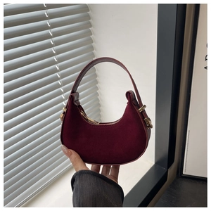 Close-up of burgundy crescent bag featuring gold zipper and premium suede leather texture