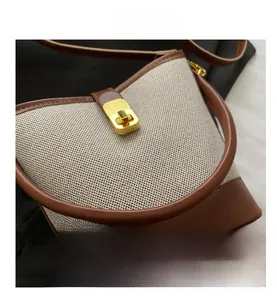 Detail view of canvas bucket bag showing gold twist lock and brown leather trim